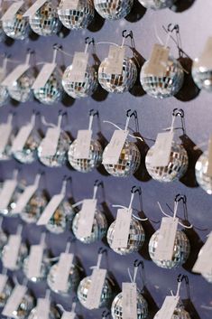 several disco ball ornaments are hanging on the wall with tags attached to each ornament