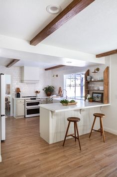 a kitchen with two stools in front of the island and an open floor plan