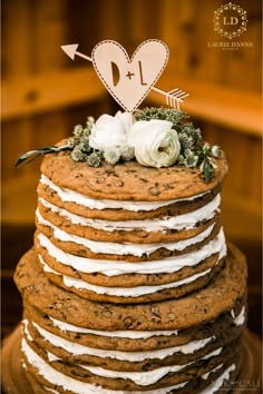 a large stack of cookies with white frosting and flowers on top is decorated with an arrow