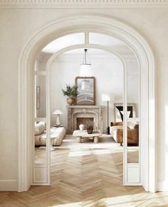 an archway leading into a living room with white walls and wood floors, along with a fireplace