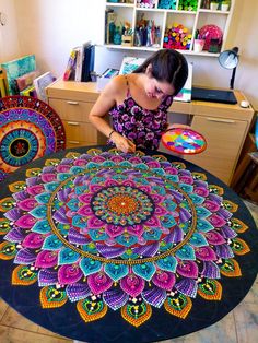 a woman is working on an intricately designed table cloth in front of her desk