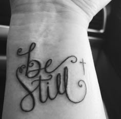 a black and white photo of a wrist tattoo with the words be still on it