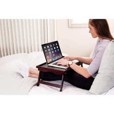 a woman sitting on a bed using a laptop computer