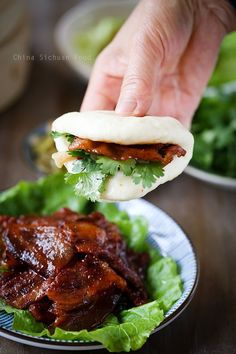 a person is dipping sauce on top of some meat in a bowl with lettuce