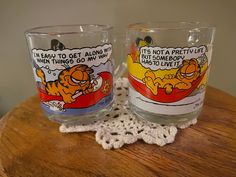 two glasses sitting on top of a wooden table with crocheted doily around them