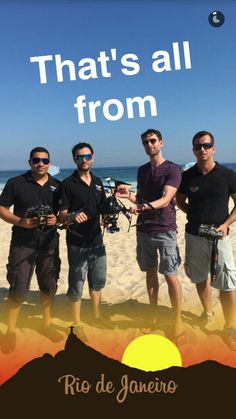 three men are standing on the beach with their arms around each other and one man is holding a camera