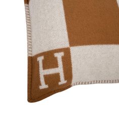 a brown and white pillow with the letter h on it