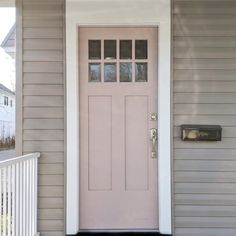 a pink front door on a gray house with white railings and two sidelights