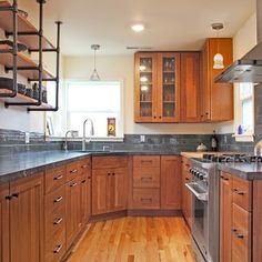 a kitchen with wooden cabinets and stainless steel appliances in the center, along with hardwood flooring