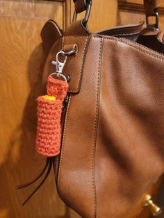 a handbag hanging from a hook on a wooden door with a crocheted keychain