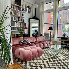 a living room filled with lots of furniture next to large windows and a black and white checkered floor