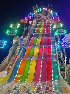 a brightly lit carnival ride at night with lights on it's sides and colorful slides