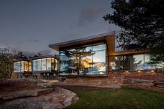 a modern house with large windows on the side of it's face at night