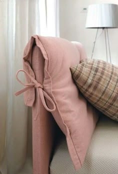 a pink couch with two pillows tied to it's back and one pillow on the other side