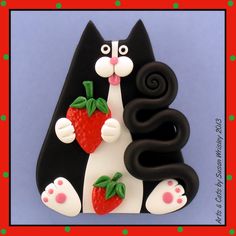 a black and white cat with strawberries on it's tail sitting in front of a red frame