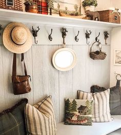 a bench with pillows and hats hanging on the wall next to it is filled with other items