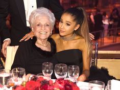 an older woman sitting next to a younger woman at a table with wine glasses on it