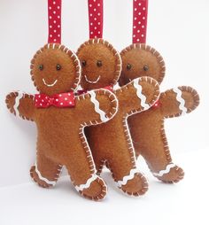 four gingerbread man ornaments hanging from red ribbon