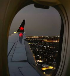 the view from an airplane window at night with lights on and buildings in the distance