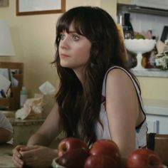 two people sitting at a table with apples in front of them and one person looking up