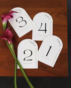 the table numbers are laid out on top of each other with a single flower in front of them