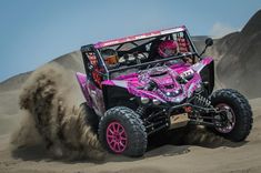 a pink and black buggy driving through the sand