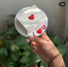 a person holding up a piece of paper with the word love on it and two hearts