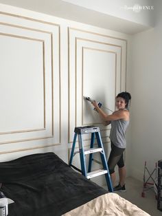 a woman is painting the walls in her bedroom with paint rollers and a ladder