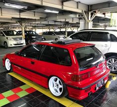 two cars parked in a parking garage next to each other with their hoods down