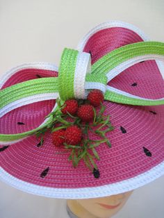 "* This design features the watermelon braiding as the hat foundation folded into design loops complemented by red raspberries and summer greens. * The hat form is about 12\" folded in back and tilted in a sophisticated design. * It is light weight, balanced and comfortable to wear year round. * Designed on a satin covered metal headband, it fits just about any head size and when viewed from any direction it looks complete, striking and eye catching. * Wear it throughout the year for special eve Green Mini Hat For Kentucky Derby And Beach, Red Summer Hats For Garden Party, Handmade Red Straw Hat For Summer, Red Adjustable Hat For Garden Party, Handmade Red Straw Hat With Curved Brim, Melon Hat, Whimsical Green Mini Hats For Summer, Fruit Hat, Handmade Red Summer Hat