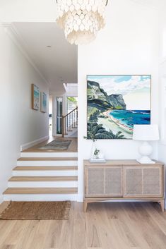 an entryway with stairs leading up to the second floor and a painting on the wall