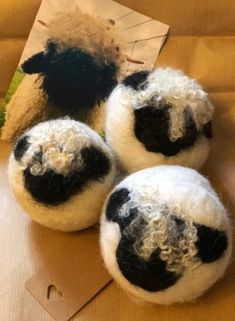 three black and white sheep balls sitting on top of a cardboard box