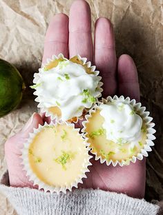 two small cupcakes with white frosting and lime zest on top in someone's hand