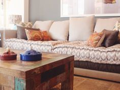 a living room filled with furniture and pillows on top of a wooden table in front of a window