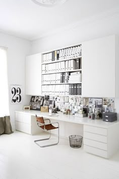 an office with white walls and shelves filled with books