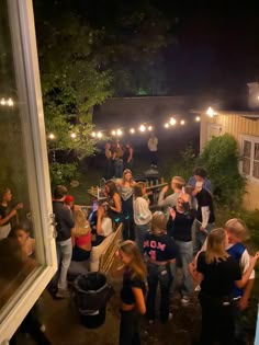 a group of people standing around each other in front of a building with lights on