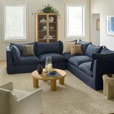 a living room filled with blue couches and chairs next to a coffee table in front of two windows