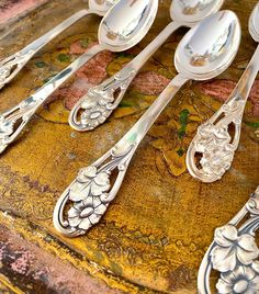 there are many silver spoons and forks on the table with floral designs around them