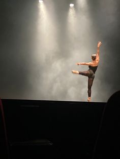 a man standing on top of a stage with his arms in the air as he performs an acrobatic move