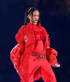 a woman in a red outfit is performing on stage