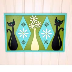 a door hanger with three black cats and flowers on it's front wall