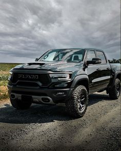 a black truck parked on the side of a dirt road