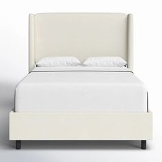 a bed with white linens and pillows on it's headboard is shown