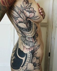 a woman's stomach with tattoos on it and flowers in the middle of her body