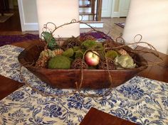 a wooden bowl filled with fruit on top of a blue and white tablecloth covered floor