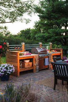 an outdoor kitchen with grill, table and chairs