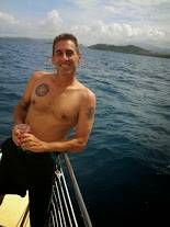 a man standing on the front of a boat in the ocean with his shirt off