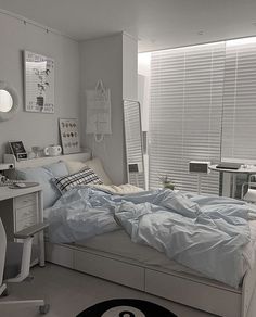 a bed sitting in a bedroom next to a white desk and window covered with blinds