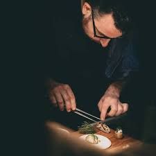 a man cutting up food on top of a wooden table