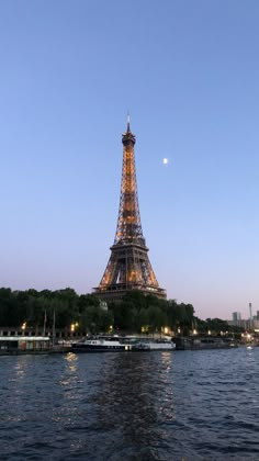 the eiffel tower is lit up at night from across the river in paris